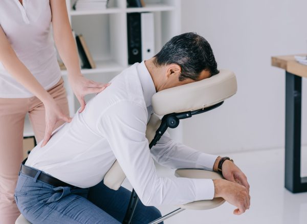 masseuse doing back massage on seat at office
