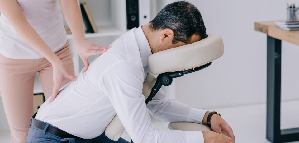 masseuse doing back massage on seat at office